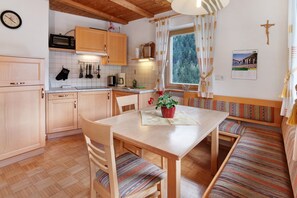 Una cocina acogedora con armarios de madera, un microondas y un comedor con bancos y una mesa.