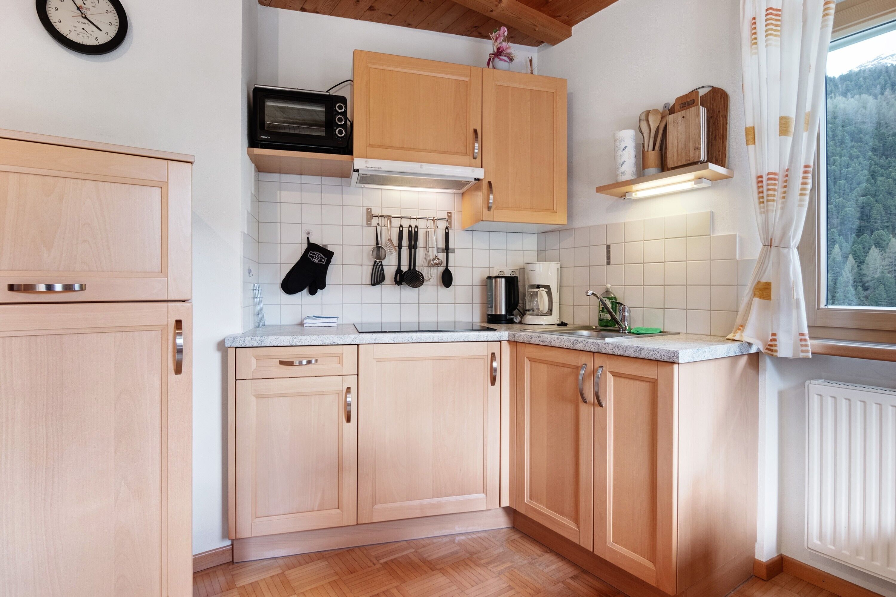Une cuisine avec des meubles en bois, un four à micro-ondes, une machine à café et une fenêtre avec des rideaux.