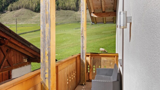 A balcony with a view of a green field and a wooden structure. - Apartment "Edelweiss" with mountain view, private terrace and Wi-Fi (Curon Venosta)
