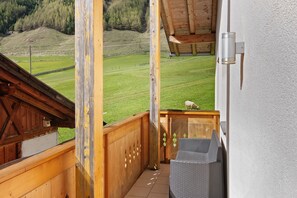 A balcony with a view of a green field and a wooden structure.
