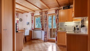Una cocina con armarios de madera, un radiador, una ventana con cortinas y vistas a árboles.