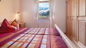 Un dormitorio con una cama, una ventana con cortinas, un armario de madera y una lámpara fijada a la pared.