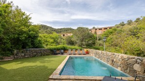 A swimming pool with stone walls, a grassy lawn, and a stone patio with outdoor furniture. - Villa 'Casa Argentera' with Mountain View, Private Pool and Wi-Fi (L'Argentera)