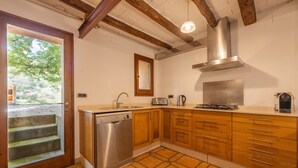 A kitchen with wooden cabinets, a dishwasher, a stove, and a window with a view of greenery. - Villa 'Casa Argentera' with Mountain View, Private Pool and Wi-Fi (L'Argentera)
