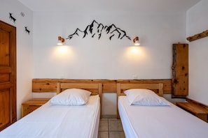 A room with two wooden beds, a wooden headboard, a wall-mounted mountain decoration, and a wooden cabinet. - Apartment 'La Favière' with Mountain View, Balcony and Wi-Fi (Val-Cenis)