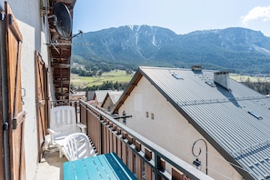 A balcony with a view of mountains, a wooden chair, and a table. - Apartment 'La Favière' with Mountain View, Balcony and Wi-Fi (Val-Cenis)