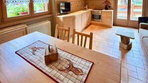 Un interior de madera con una mesa de comedor, sillas, una zona de cocina y vistas a través del ventanal.