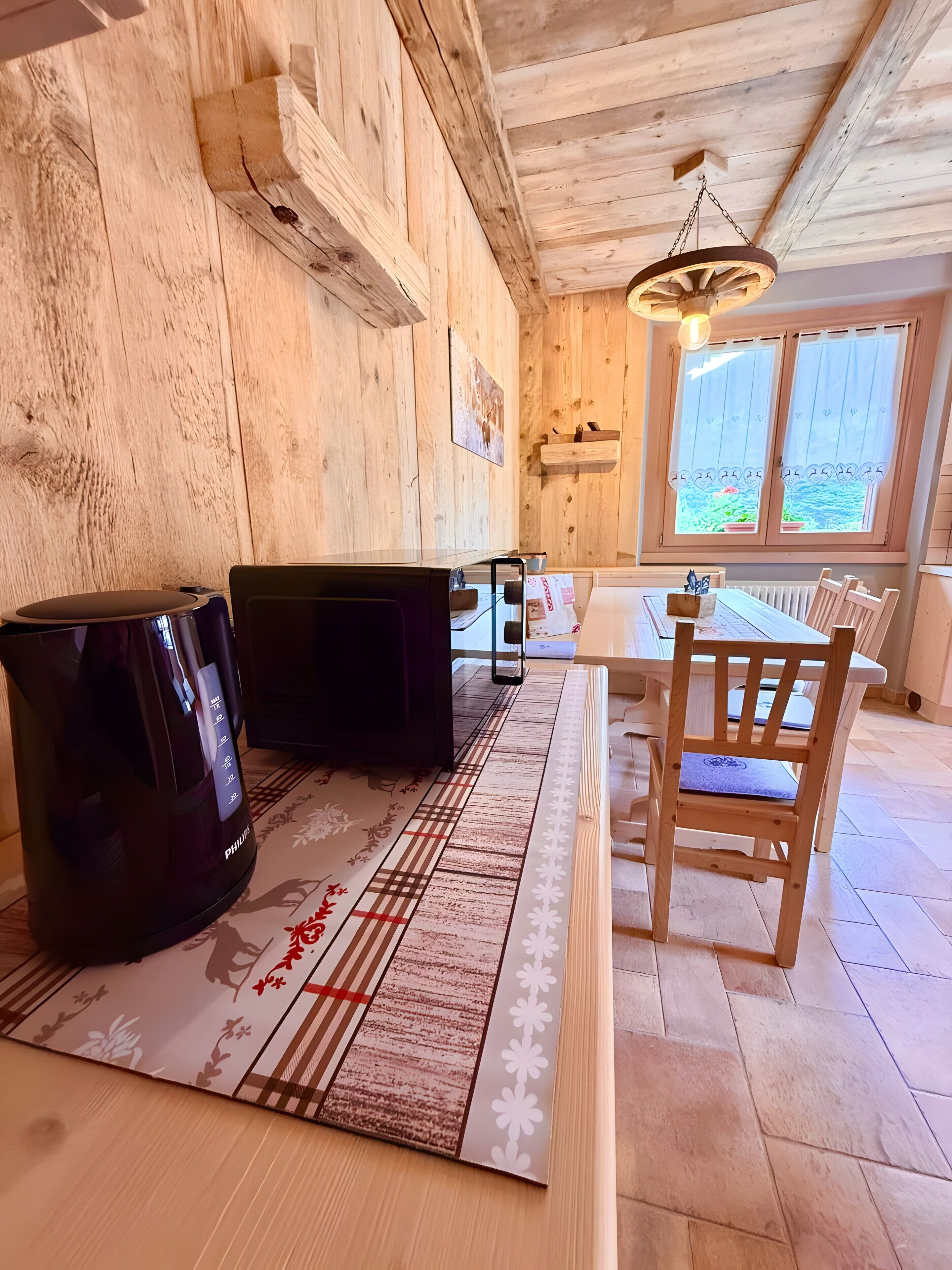 A wooden interior with a table, chairs, a black appliance, and a hanging light fixture.