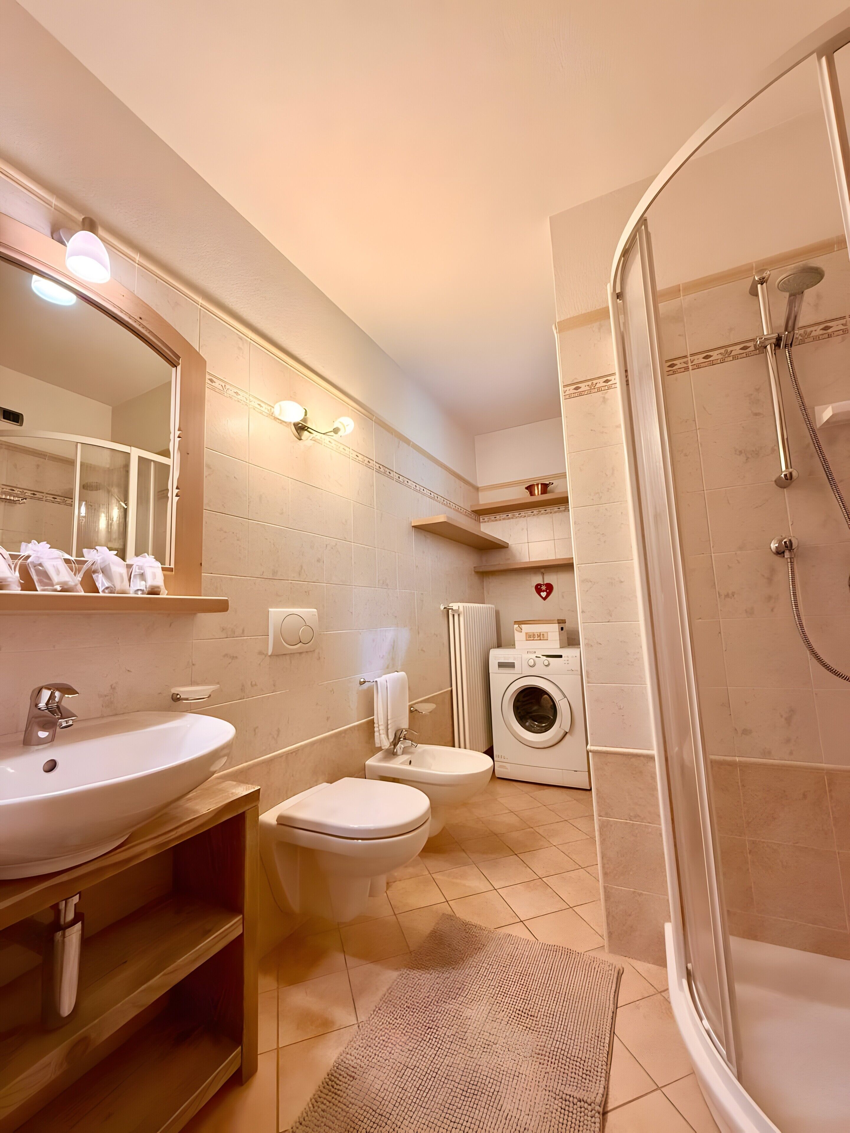 Une salle de bain moderne équipée d’un lavabo, de toilettes, d’un bidet, d’une douche et d’un lave-linge.