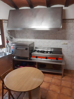 A kitchen with a gas stove, a built-in oven, a sink, and a round wooden table.