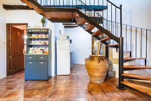 A bakery shop, a white refrigerator, a large vase, and a wooden staircase.