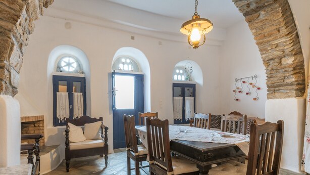 A dining area with a table, chairs, and a hanging light fixture.