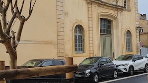 Un bâtiment à la façade beige, doté de fenêtres en arc de cercle et d’une entrée centrale.