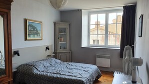 Une chambre à coucher avec un lit, une fenêtre donnant sur un paysage agréable, un radiateur et un placard.