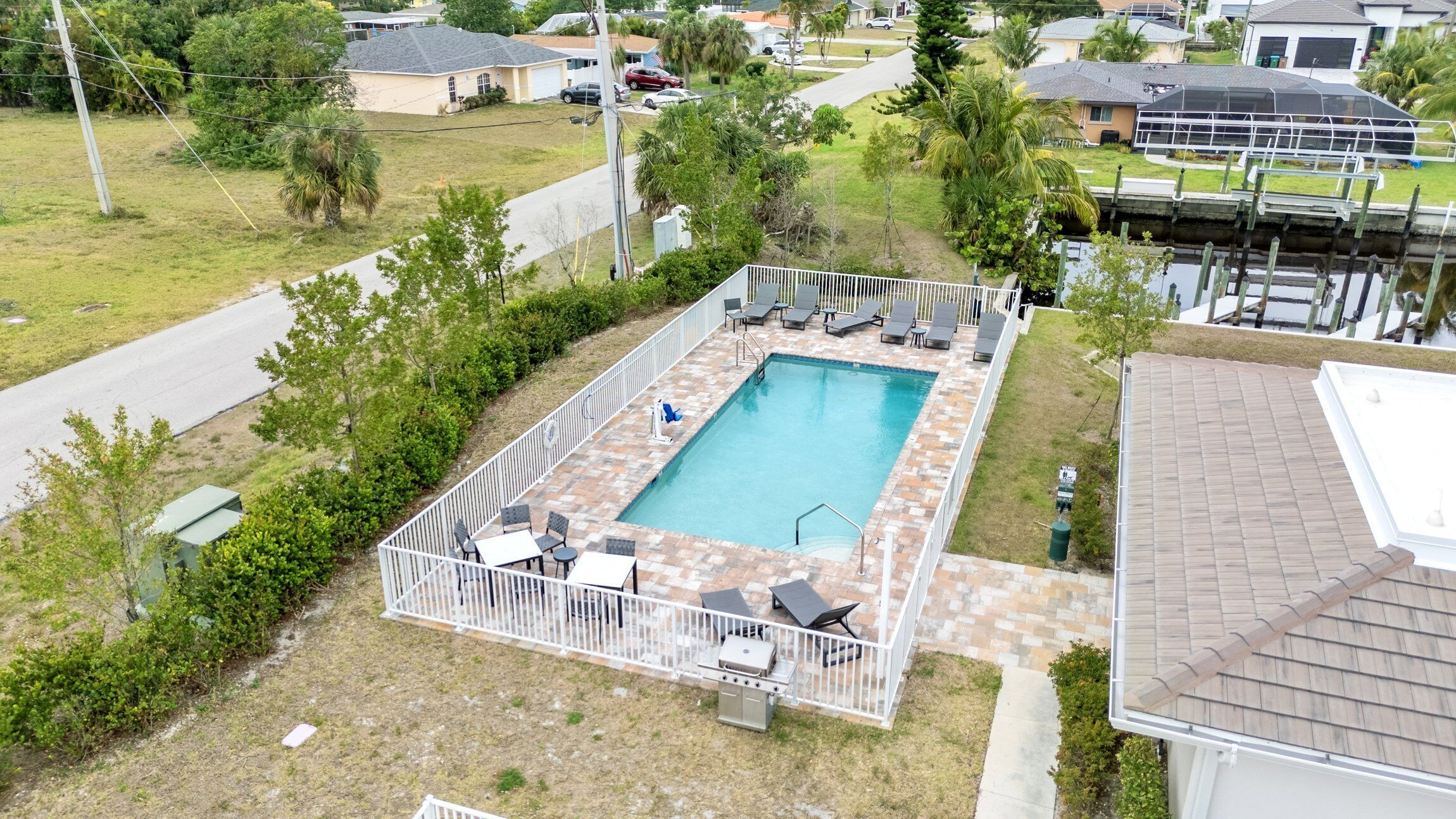 Vista aérea de una zona residencial con una piscina rectangular rodeada por una valla blanca.