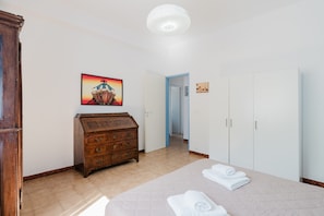 Un dormitorio con una cama, un aparador de madera, un cuadro y un armario.