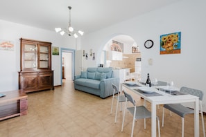 Una sala moderna con sofá, mesa de comedor, sillas y un aparador.