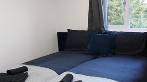 A bedroom with a bed, pillows, a window with curtains, and a view of trees. - 6BV Apartment - Bevois Valley (Southampton)