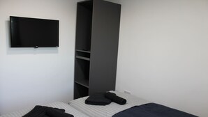 A bedroom with a bed, a flat-screen TV mounted on the wall, and a wardrobe. - 6BV Apartment - Bevois Valley (Southampton)