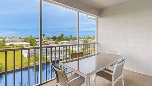 A balcony with a table and chairs, overlooking a body of water and a residential area. - Gulf Access with Boat Slip, Heated Saltwater Pool, Dog-Friendly - Bacino Vista #301 - Roelens (Cape Coral)