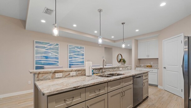 A modern kitchen with a marble countertop, stainless steel appliances, and pendant lighting. - Gulf Access with Boat Slip, Heated Saltwater Pool, Dog-Friendly - Bacino Vista #301 - Roelens (Cape Coral)
