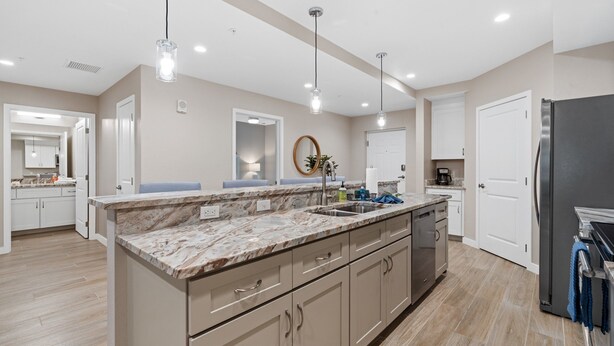 A modern kitchen with marble countertops, stainless steel appliances, and pendant lighting. - Gulf Access with Boat Slip, Heated Saltwater Pool, Dog-Friendly - Bacino Vista #206 - Roelens (Cape Coral)