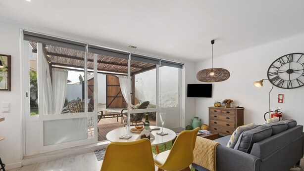 Een moderne woonkamer met een bank, eettafel, stoelen en een groot raam.