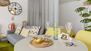 Een moderne woonkamer met een ronde tafel, een bank, een klok, een fles en een glas.