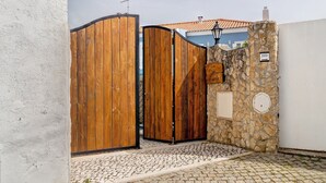 Een poort met een stenen muur en een geplaveid pad dat naar een gebouw leidt.