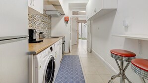 A narrow kitchen with a washing machine, a coffee machine, and a patterned backsplash. - Apartment 'Lisboa Sweet For Familys' with Private Terrace, Wi-Fi and Air Conditioning (Lisboa)
