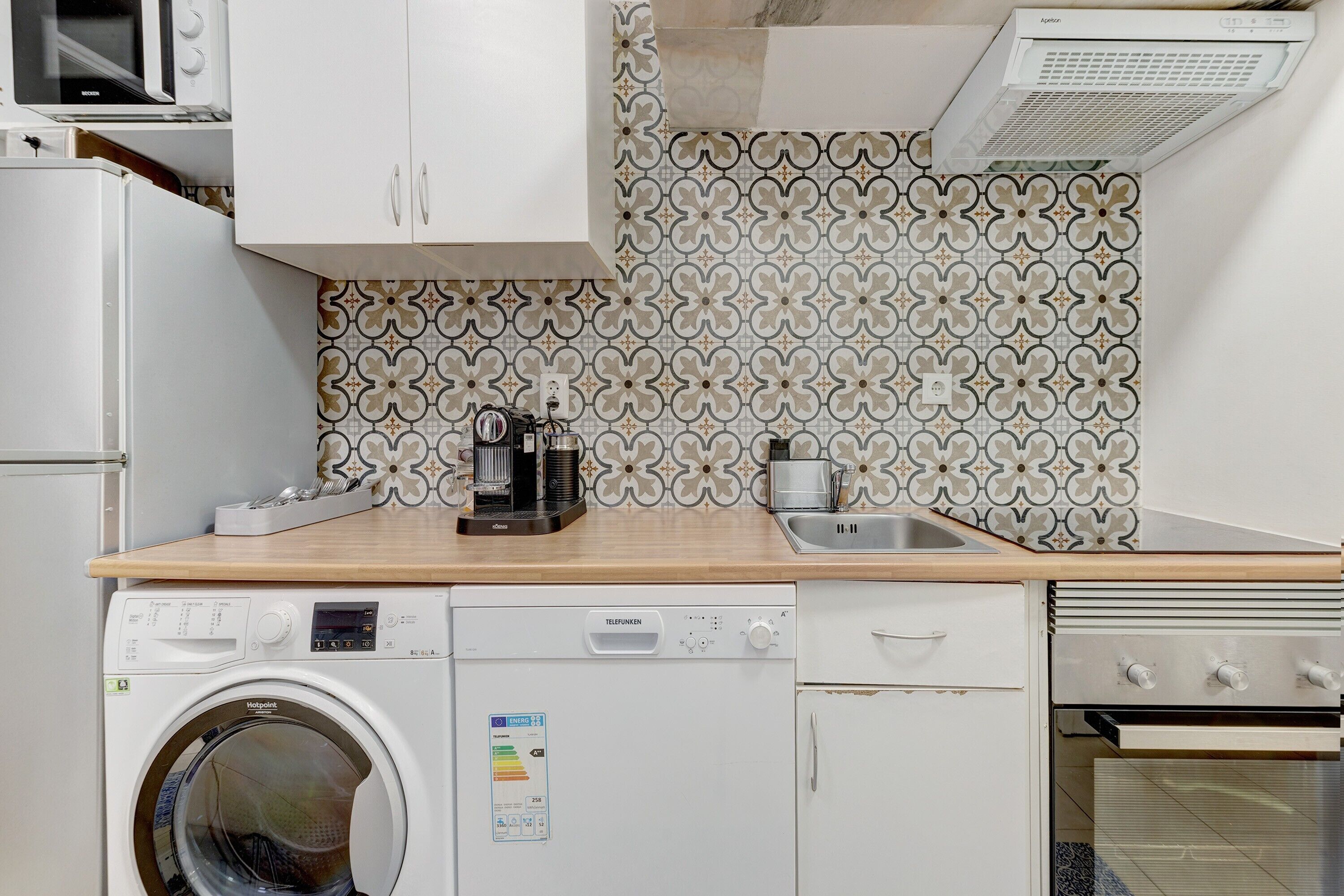 A compact kitchen with a washing machine, a microwave, a coffee maker, and a toaster.