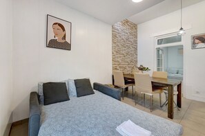 Quarto com cama, mesa de jantar, cadeiras, janela e obras de arte nas paredes.