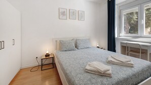 A bedroom with a bed, bedside lamps, a desk, and a window with curtains. - Apartment 'Lisboa Sweet For Familys' with Private Terrace, Wi-Fi and Air Conditioning (Lisboa)