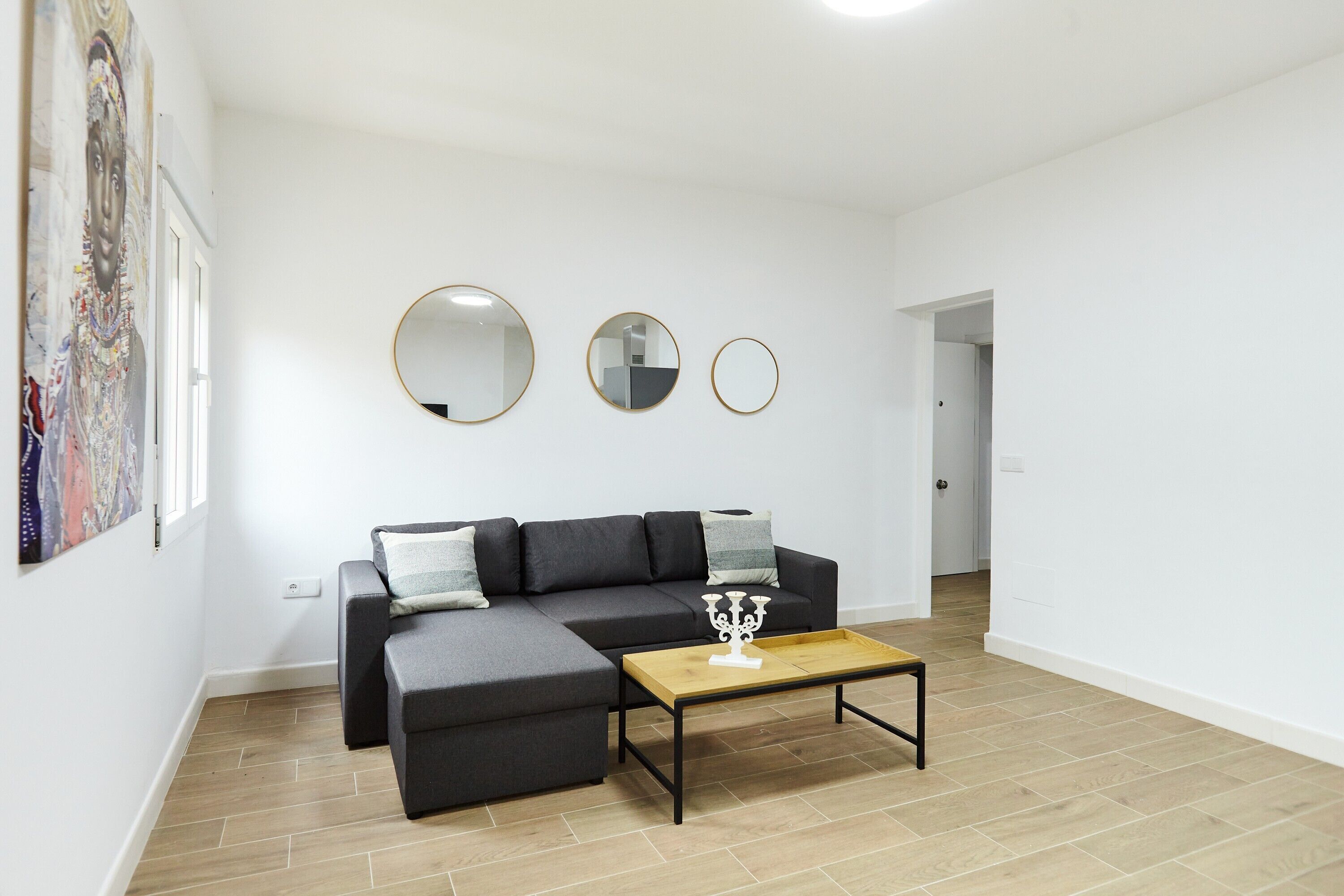 A modern living room with a sectional sofa, a coffee table, and three wall-mounted mirrors.