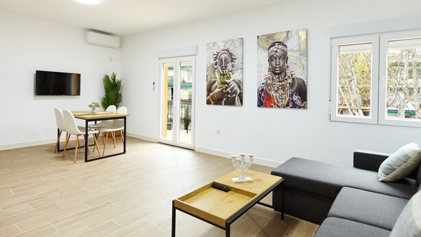 A modern living room with a sofa, a coffee table, a TV, and artwork on the wall.
