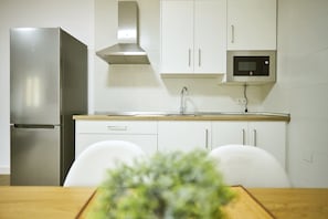 Ett modernt kök med ett kylskåp i rostfritt stål, en mikrovågsugn och vita skåp.