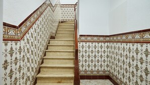 Un escalier dont les murs sont décorés de motifs ouvragés et qui est muni d’une main courante en bois.