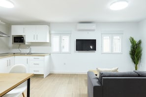 A modern kitchen with white cabinets, a microwave, and a flat-screen TV.