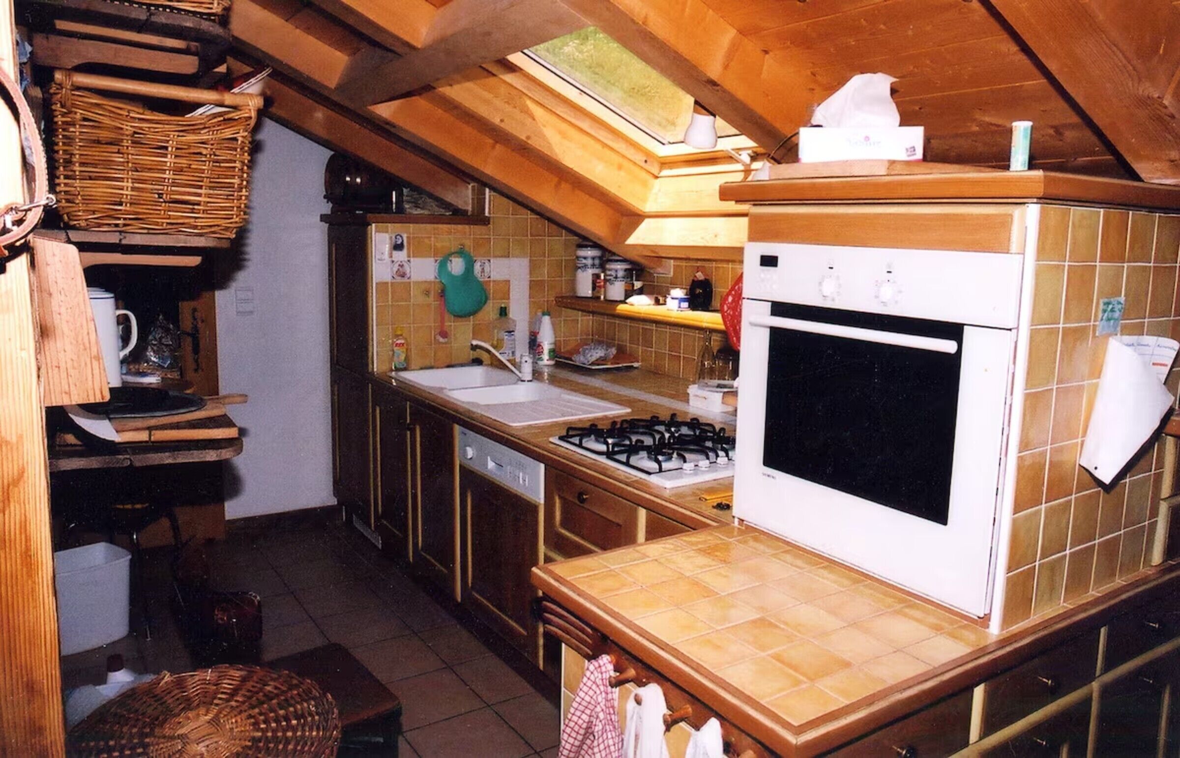 A kitchen with a gas stove, oven, and a window above the sink.