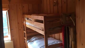 Une cabane en bois avec des lits superposés, un radiateur et un luminaire au plafond.