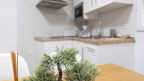 Une cuisine moderne avec des meubles blancs, un plan de travail en bois et une petite plante d’intérieur posée sur la table.