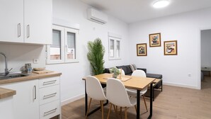 Une cuisine moderne avec des meubles blancs, un plan de travail en bois et un coin repas comprenant une table et des chaises.