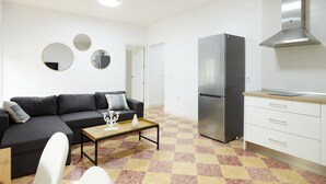 Ein modernes Wohnzimmer mit Sofa, Couchtisch und Küchenzeile, einschließlich Kühlschrank und Herd.