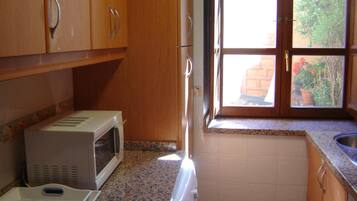 A kitchen with wooden cabinets, a microwave, a window with a view of greenery, and a granite countertop.
