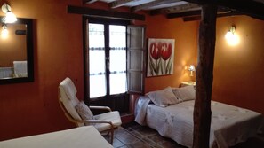 Une pièce comprenant un lit, une chaise, une table, une fenêtre et un tableau accroché au mur.