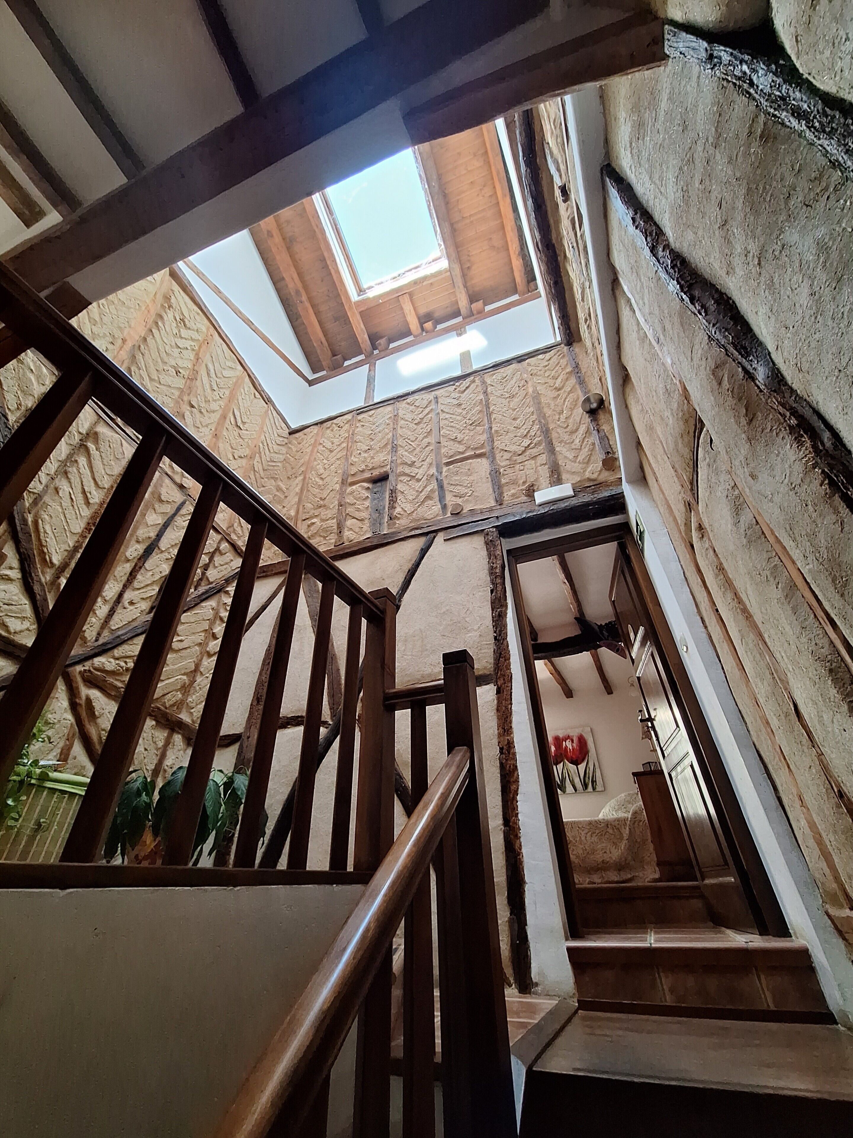 Un escalier en bois, surmonté d’une lucarne, mène à un niveau inférieur.