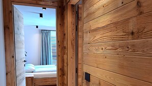 A wooden-paneled hallway leading to a bedroom with a bed and a window. - Apartment 'Livigno' with Mountain View, Private Terrace and Wi-Fi (Livigno)