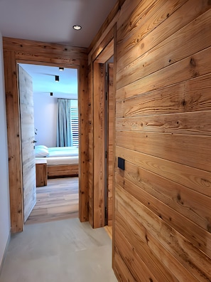 A wooden-paneled hallway leading to a bedroom with a bed and a window. - Apartment 'Livigno' with Mountain View, Private Terrace and Wi-Fi (Livigno)