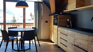 A modern kitchen with wooden cabinets and a dining area with a round table and chairs. - Apartment 'Livigno' with Mountain View, Private Terrace and Wi-Fi (Livigno)