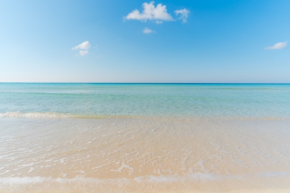 A beach with clear water and a sandy shore.